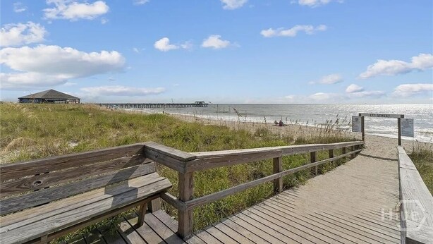 A wooden boardwalk leading to a beach with a pier in the background. - Beach Block with ocean views in downtown Tybee Island (Tybee Island)