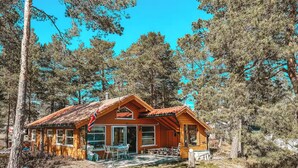 Une cabane en bois avec un toit rouge, entourée d’arbres.