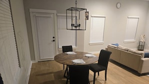Et spiseområde med et rundt bord, stole og en hængende lampe.