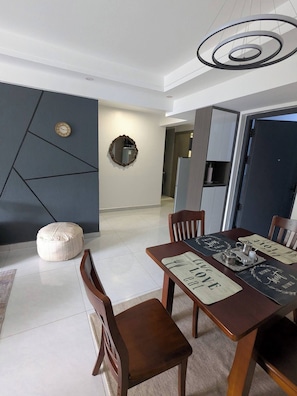 A modern dining area with a wooden table, chairs, and a decorative mirror on the wall. - Chic 2BR with Gym & Skyline views - Westlands (Nairobi)