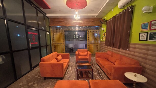 A lobby with orange sofas, a patterned rug, and a ceiling light fixture. - DEE DASH INN (Bhubaneshwar)