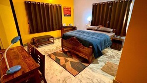 A bedroom with a bed, bedside tables, a desk, and a chair. - DEE DASH INN (Bhubaneshwar)