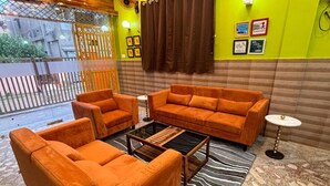 A room with orange sofas, a glass coffee table, a zebra-patterned rug, and a small round table. - DEE DASH INN (Bhubaneshwar)