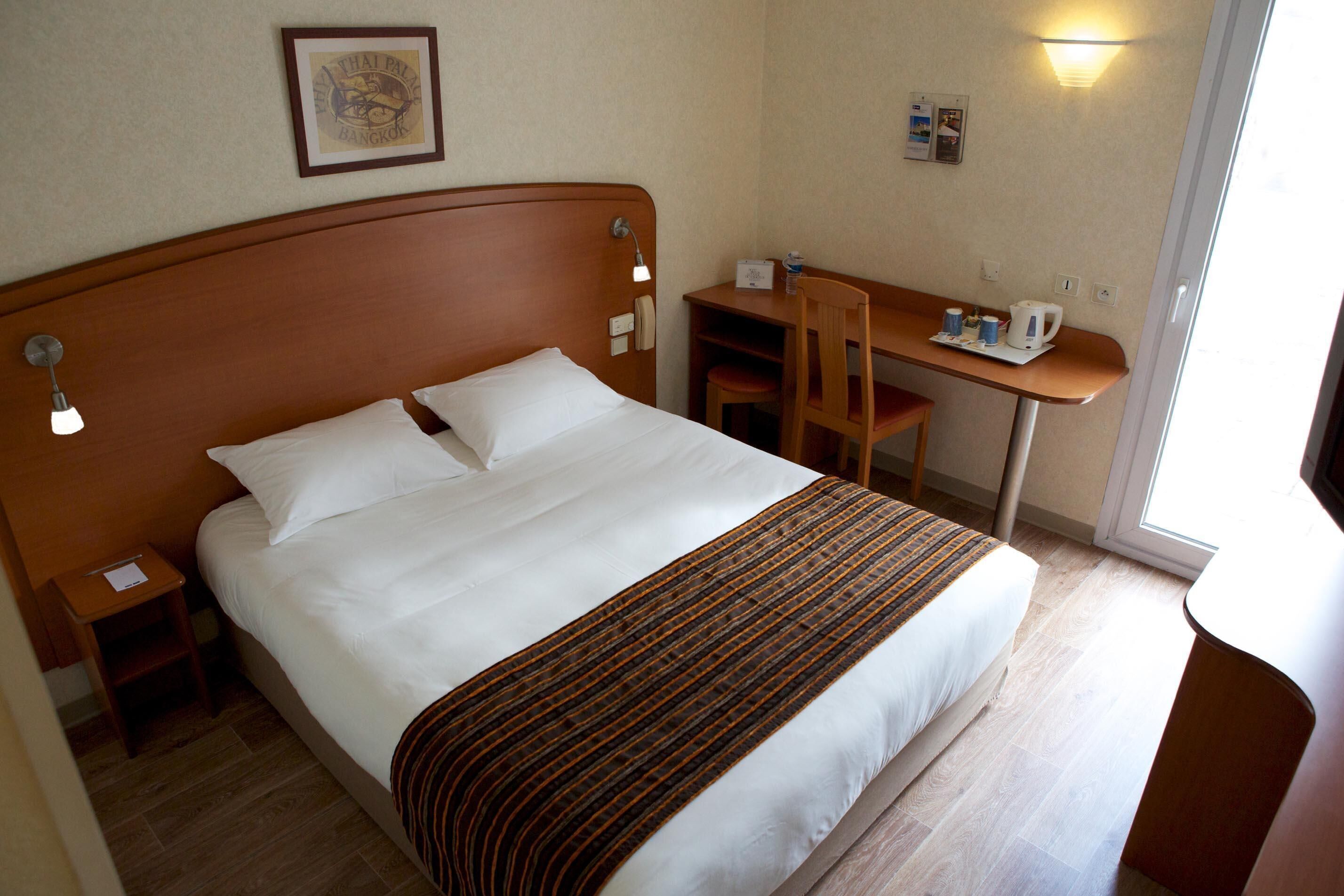 Ein Hotelzimmer mit Bett, Schreibtisch, Stuhl und Nachttisch.