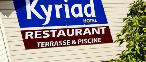Schild für das Kyriad Hotel Restaurant mit Terrasse und Pool.