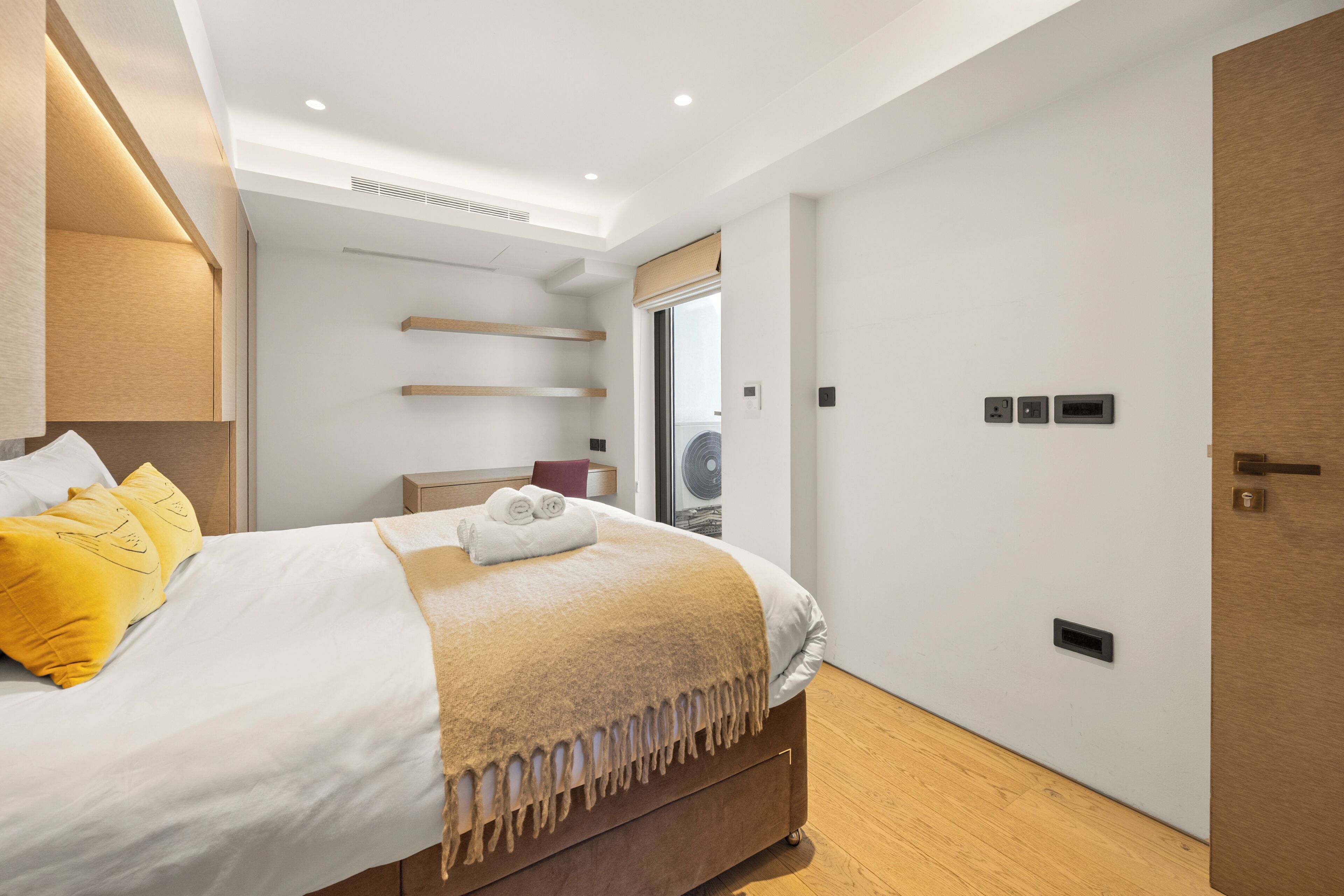 A modern bedroom with a bed, bedside tables, a wardrobe, and a window.