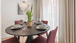 Una mesa redonda de comedor con platos, vasos y una planta como centro.