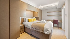 Un dormitorio moderno con cama, mesitas de noche, un escritorio y una silla.