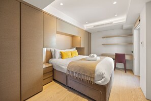 Ein modernes Schlafzimmer mit Bett, Nachttischen, einem Schreibtisch und einem Stuhl.