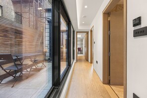 Ein Korridor mit Holzboden, einer Glasschranke und einer Bank mit Stühlen.