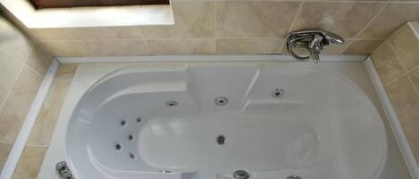 A modern bathroom with a freestanding bathtub, a skylight, and a shower area.
