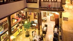 A traditional building with a courtyard, multiple dining areas, and a central seating area with a tree.