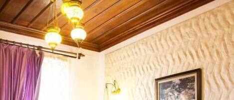 A hotel room with two beds, a wooden ceiling, a patterned wall, and a painting.