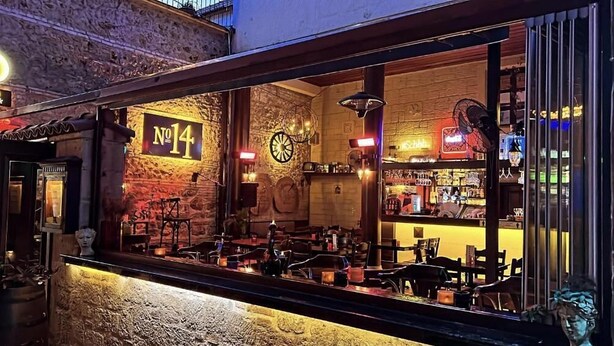 A bar with a rustic interior, a clock, and a sign indicating 'No 14'.