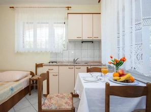 Una cocina compacta con comedor, una cama y un ventanal con cortinas.