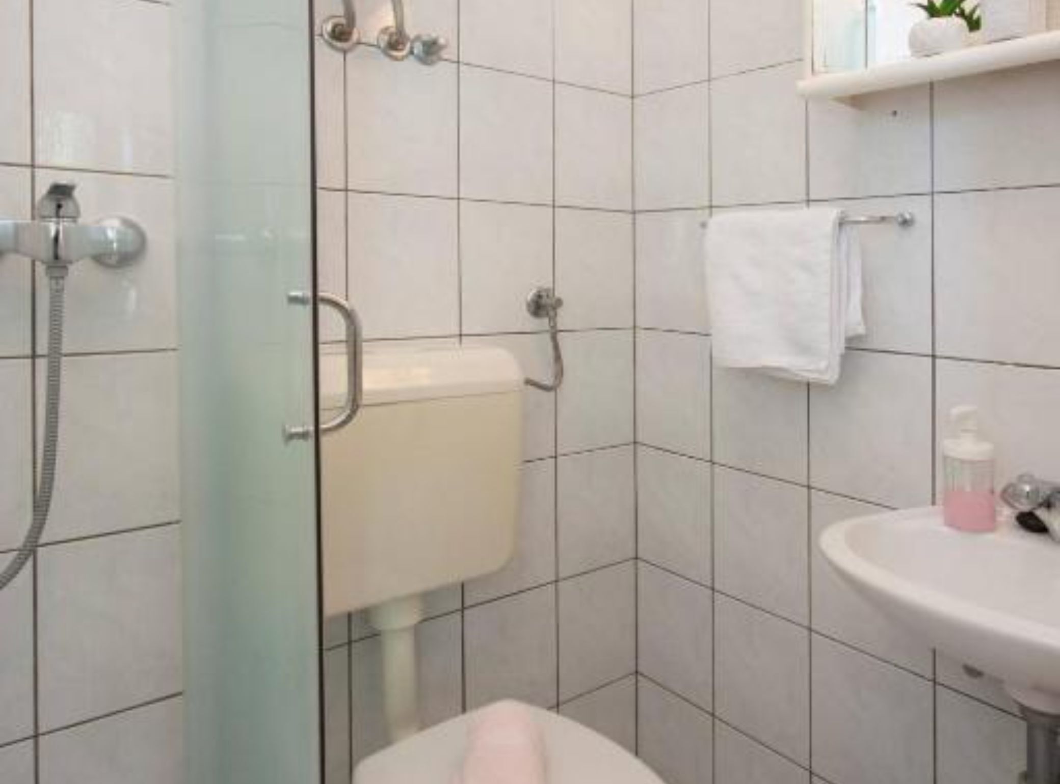 Ein Badezimmer mit Toilette, Waschbecken, Dusche und Handtuchhalter.