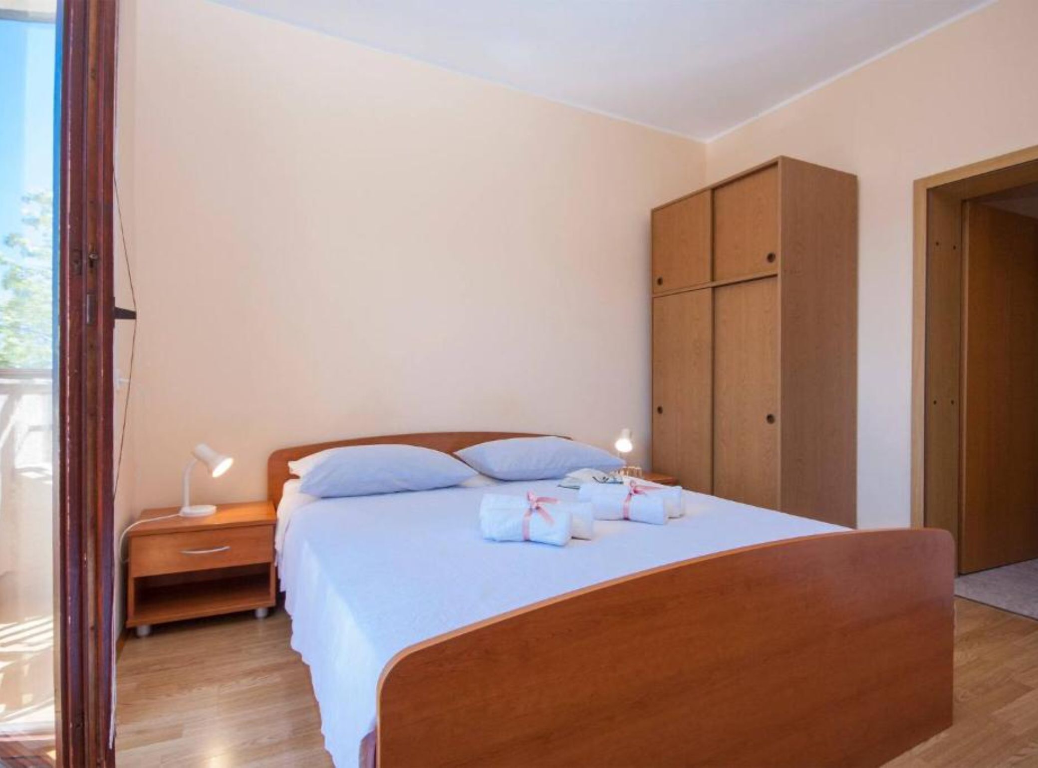 Una camera da letto con un letto di legno, comodini, un armadio e vista attraverso una porta aperta.