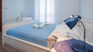 A bedroom with a bed, bedside table, lamp, air conditioning unit, and a window with curtains. - Guest House Stay & Smile Dolac Primošten (Primosten)