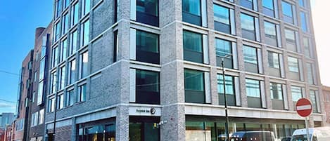 A multi-story building with a modern architectural design, featuring a prominent corner entrance, large windows, and a visible 'Pryor's Inn' sign.