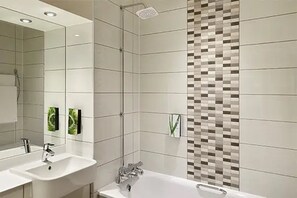 A modern bathroom with two sinks, a shower, and a tiled wall with a mosaic pattern. - Premier Inn Dublin City Centre (Dublin)