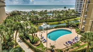 Ein Resort mit Pool, Blick auf den Strand, Palmen und einem eingezäunten Bereich.