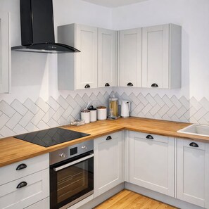 A modern kitchen with white cabinetry, a black range hood, a wooden countertop, and a built-in oven. - Central Home, Great for Couples, Free Parking (Cardiff)