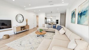 A modern living room with a beige sofa, a coffee table, and a TV on a stand.