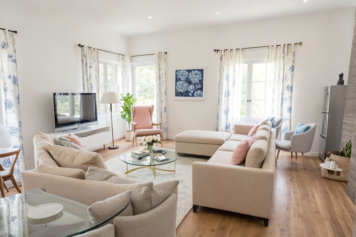 A modern living room with a flat-screen TV, sofas, a glass coffee table, and a potted plant.