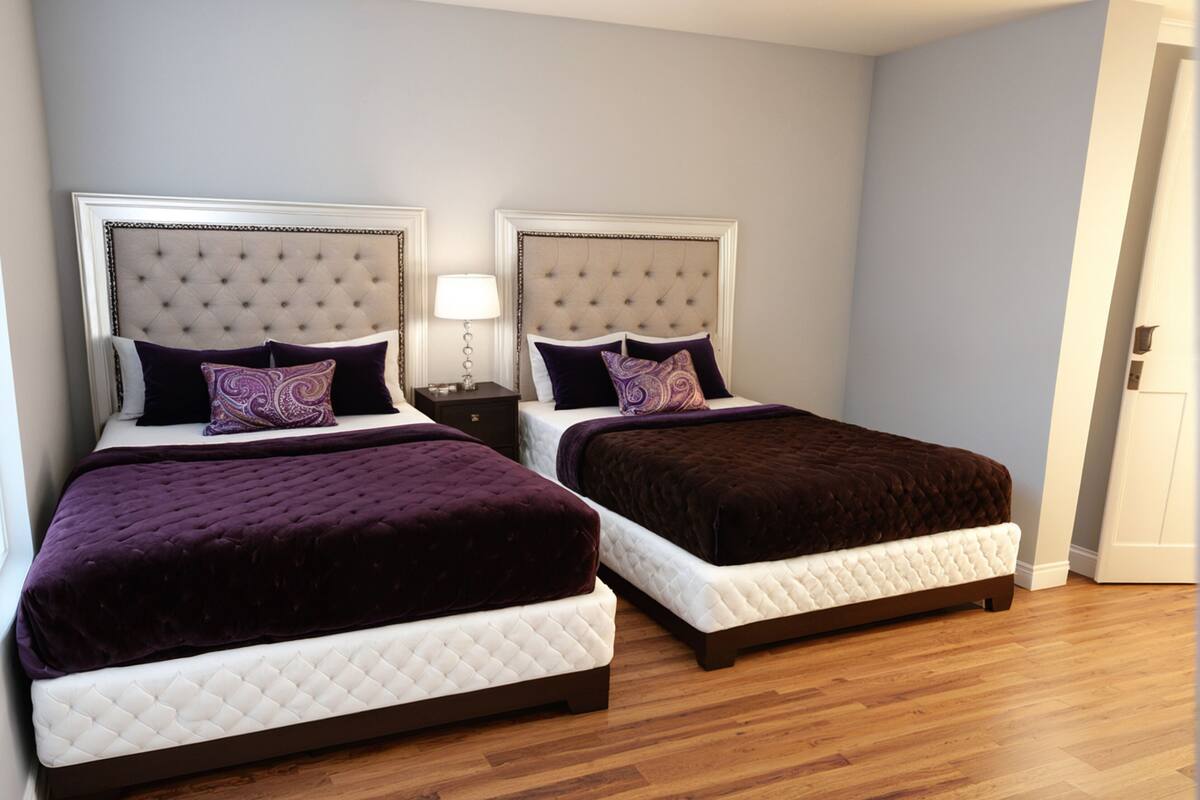 Ein Hotelzimmer mit zwei Queensize-Betten, einem Nachttisch und einer Tür.