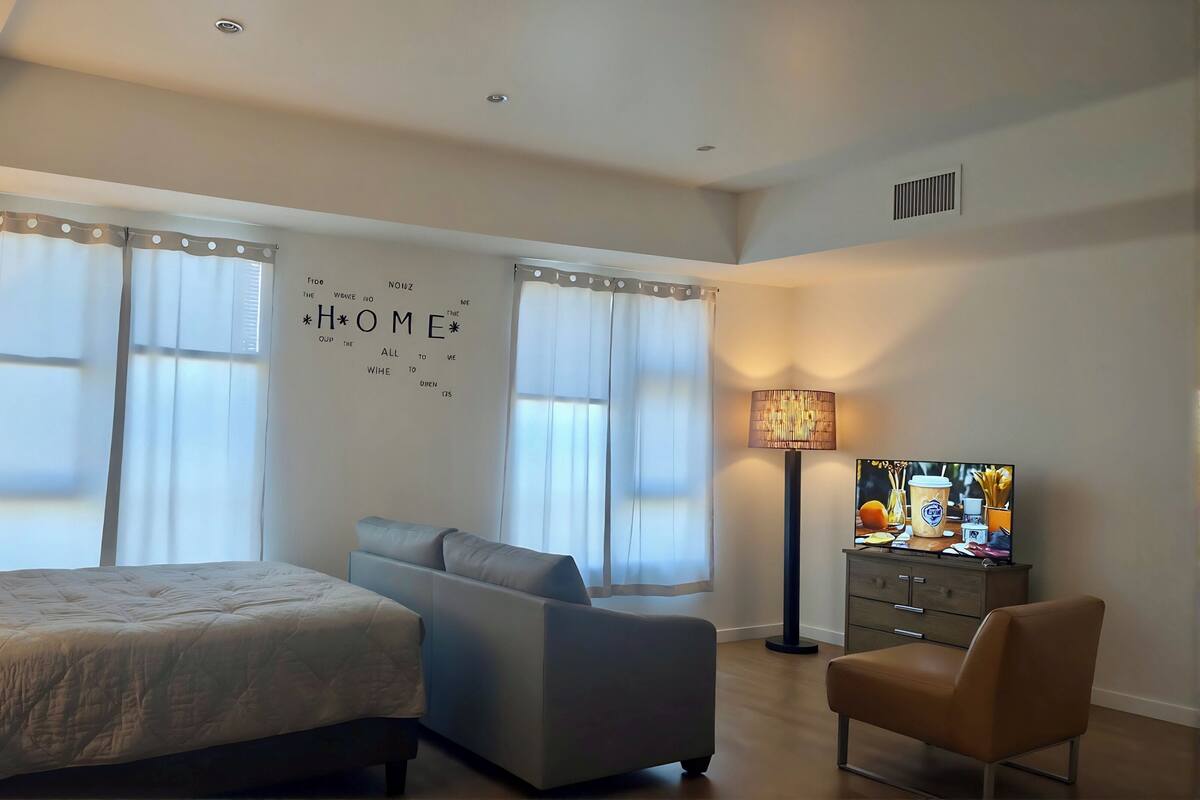Ein Schlafzimmer mit einem Bett, einem Schlafsofa, einem Sessel, einem Fernseher und einer Wand mit motivierenden Sprüchen.