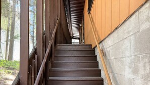 A wooden staircase leading to a covered area with a view of trees. - Lake Minocqua Island Home - Walk to Town - Sleep 6 (Minocqua)