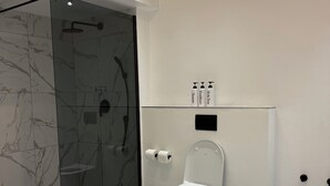A modern bathroom with a glass shower enclosure, a toilet, and a marble-tiled floor. - Boutique African-inspired Luxury 1BR in Central Cape Town with Parking (Cape Town)