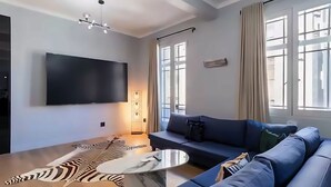 A modern living room with a flat-screen TV, a sofa, a coffee table, and a zebra-patterned rug. - Boutique African-inspired Luxury 1BR in Central Cape Town with Parking (Cape Town)