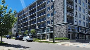 A multi-story building with balconies, a parking lot, and a clear sky.