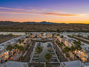 A marina with boats docked, a pool area, and a hotel with multiple floors and balconies overlooking the water.