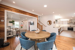 Eine moderne Küche mit weißen Schränken, Holzboden und einem Essbereich mit rundem Tisch und blauen Stühlen.