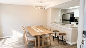 Une cuisine moderne avec un coin repas, comprenant une table en bois, des chaises et un îlot central intégré avec un évier et une cuisinière.