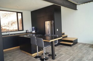A modern kitchen with a central island, a built-in refrigerator, and a dining area with a table and chairs. - Beautiful Loft – Forest – Lake View – Jacuzzi (san gaspar)