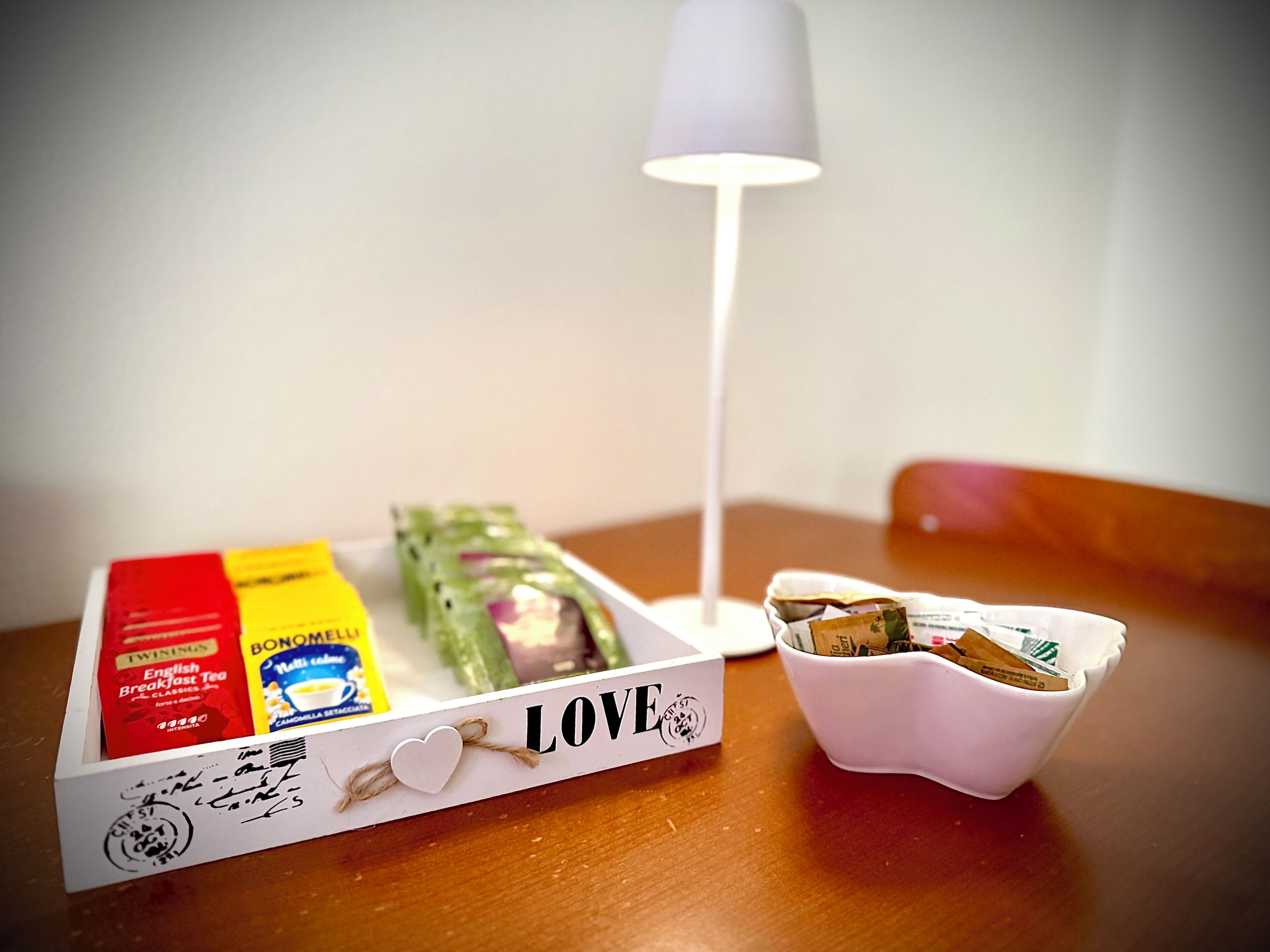 A table with a box of English Breakfast Tea, a box of Bon Ami, a lamp, and a bowl with tea bags.