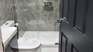 Un baño con inodoro, cabina de ducha y puerta.