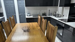 Una cocina moderna con gabinetes negros, una mesa de comedor de madera y un horno empotrado.
