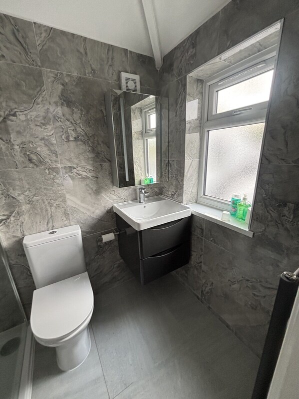 Un baño con inodoro, lavamanos, espejo y ventana.