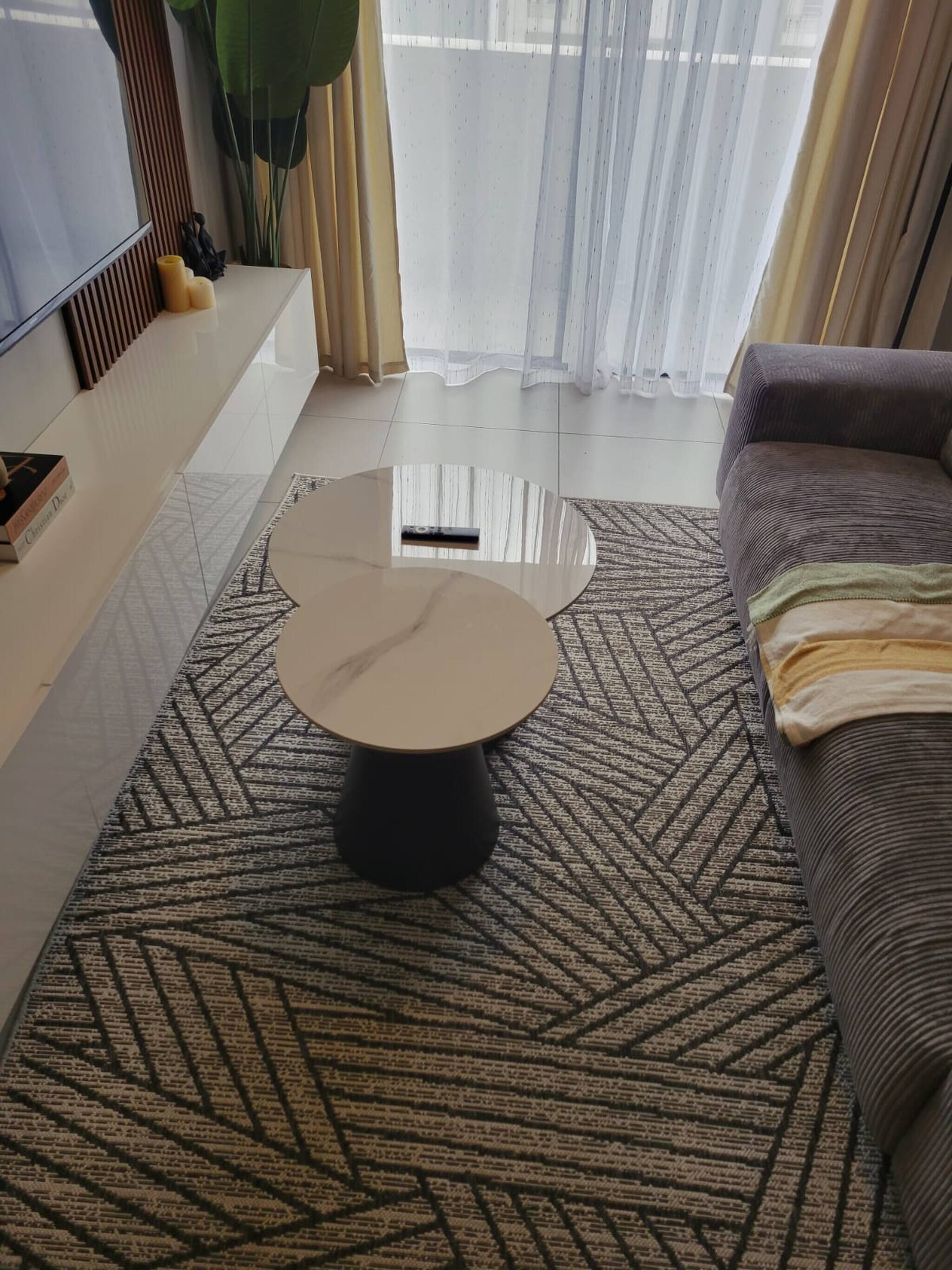 A living room with a round coffee table, a sofa, a TV, and a patterned rug.
