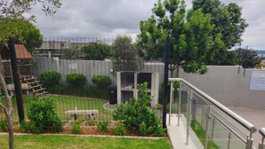 A fenced outdoor area with a picnic table, a wooden climbing structure, and a grassy lawn. - Cozy 1-bed in Midrand (Johannesburg)