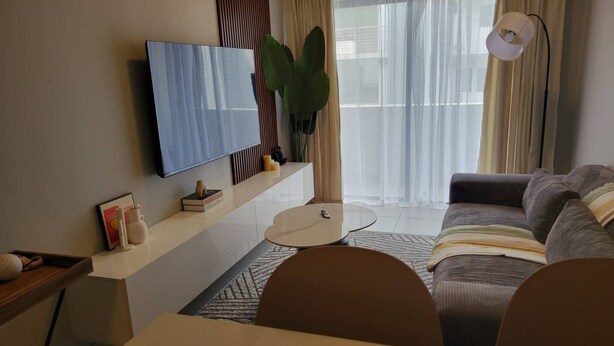 A modern living room with a flat-screen TV, a sofa, a dining table, and a lamp. - Cozy 1-bed in Midrand (Johannesburg)