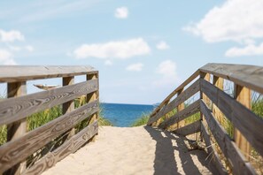 Een houten looppad naar een strand, met heldere luchten.