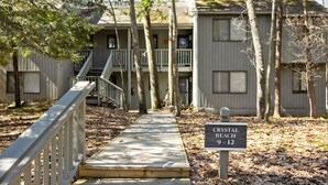 A wooden deck leading to a building with a sign indicating 'CRYSTAL BEACH 9-12'. - NEW! Dune and Drift at Crystal Beach 10 (Glen Arbor)