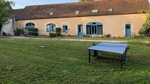 Ein Gebäude mit Ziegeldach, Rundbogenfenstern und einem Tennisplatz.