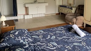 Ein Schlafzimmer mit einem Bett, einem Schminktisch, einem Frisierplatz, einer Dusche und einer Kandelaberleuchte.