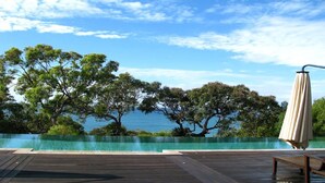 Un pontile in legno con piscina, alberi e vista sul mare.